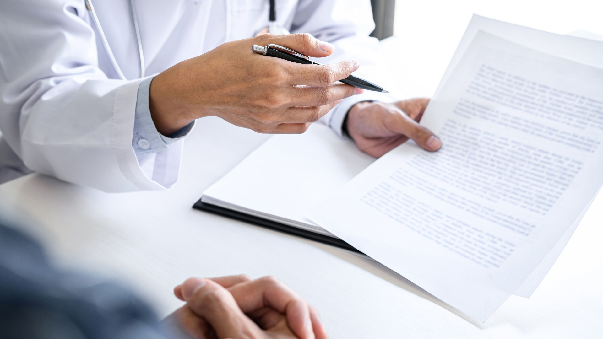 Ein Arzt füllt zusammen mit dessen Patienten seinen Reha-Antrag aus.